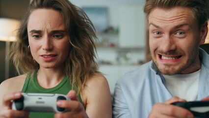Competitive pair holding gamepads home portrait. Nervous woman losing pov video