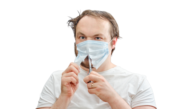 An adult man cuts a medical mask in half on his face, isolated on a white background. Concept of recovery and return to normal life after the coronavirus epidemic