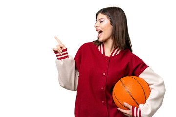 Young Russian woman playing basketball over isolated chroma key background pointing finger to the...