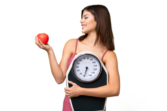 Young Russian woman with rainproof coat and umbrella over isolated chroma key background holding a weighing machine while looking an apple