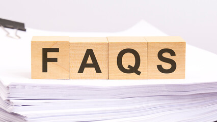 FAQS written on a wooden cube with white paper background, business concept
