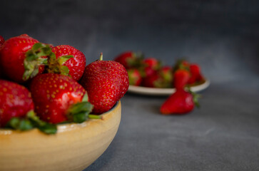 strawberries in close-up of fresh fruits with gray background and more strawberries out of focus