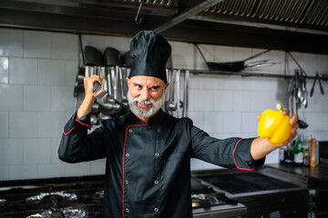 A chef in a kitchen holding a knife and a yellow pepper