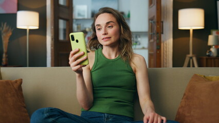 Young lady videocalling telephone sofa interior closeup. Smiling woman gossiping