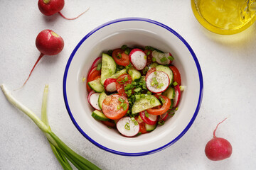 spring salad of radishes, tomatoes, cucumbers, top view, light background, no people, close-up