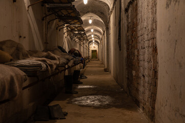 A long, gloomy hallway in an old military base with rows of beds lining the wall