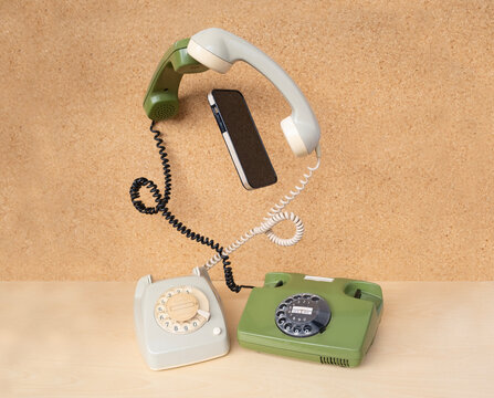 Two classic phones with levitating handsets and modern smartphone gadget, transfer technological information, experience between different generations, Bridging Past and Future