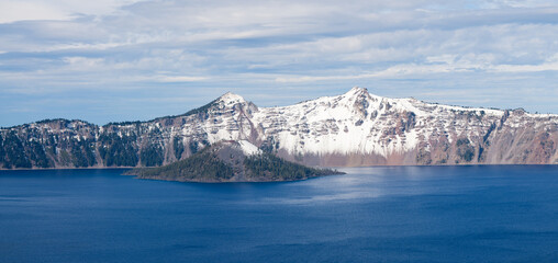 Panorama of Crater Lake blue water with Wizard Island and snow on rim
