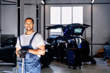 Portrait of handsome positive car mechanic repair service center cleaning using mops to roll water from the epoxy floor. In the car repair service center.