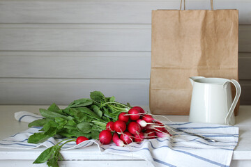 fresh radishes with tops on the kitchen table. raw vegetable, healthy food. concept: spring, rural composition, cottage core.