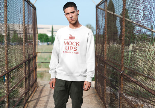 Mockup of man wearing customizable sweatshirt between wire fences