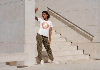 Mockup of woman leaning on urban wall wearing customizable t-shirt
