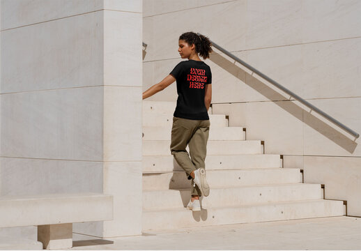 Mockup of woman wearing customizable t-shirt by steps, rear view