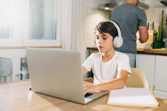 young Caucasian boy using laptop for school assignment.