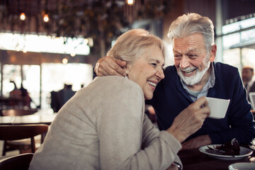 Smiling senior couple sitting in cafe having dessert