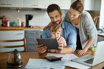 Happy parents using tablet with small daughter at home