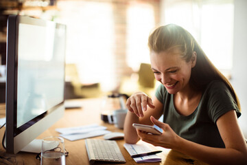 Smiling Woman Using Smartphone at Her Workspace