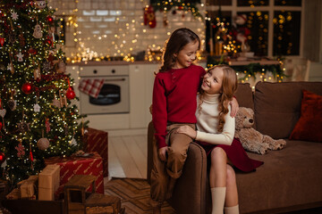 Obraz premium teenage sisters twins at home in the kitchen waiting for the New Year