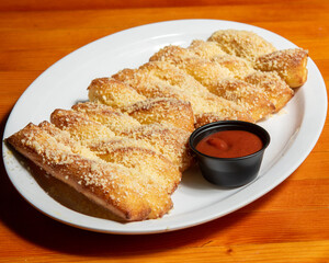 Flavored Fast Food Dish - Parmesan Breadsticks with Dipping Sauce on Indoor Table.