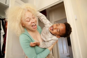 Fototapeta premium Happy mother and son playing and laughing in bedroom