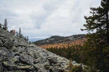 Rocky mountainside, peak covered with forest, autumn landscape in the mountains.