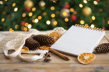 Notepad with copy space on the wooden background and natural Christmas decoration. Mockup. Eco friendly concept
