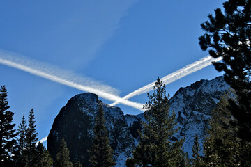  Persistent spreading Contrails cross over Sierra Nevada Mountains, Ebbetts Pass Scenic Highway, California  - obrazy, fototapety, plakaty