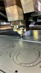 CNC laser cutting machine working with sheet metal with sparks at factory.