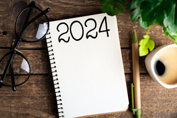 .New year resolutions 2024 on desk. 2024 goals list with notebook, coffee cup, plant on wooden...