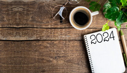 New year resolutions 2024 on desk. 2024 goals list with notebook, coffee cup, plant on wooden table. Resolutions, plan, goals, action, checklist, idea concept. New Year 2024 resolutions. Copy space - Powered by Adobe