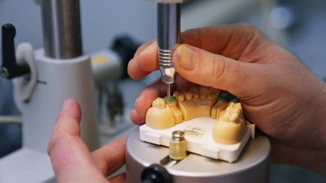 Manufacturing the model of denture. Close up. Technician's hands operating the machine tool for denture production.