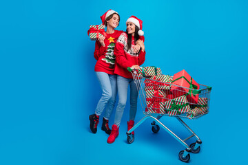 Full length photo of sweet shiny ladies santa helpers dressed print sweaters buying xmas presents...