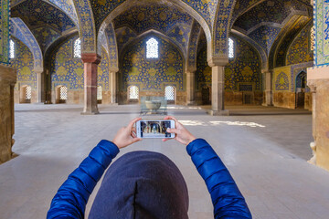 Woman photographing a mosque with her cell phone