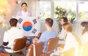 Female teacher tells the history of the state of South Korea, holding the national flag of South Korea in his hands