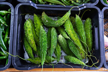 Close-up view of green bitter melons in vegetable box in outdoor grocery market