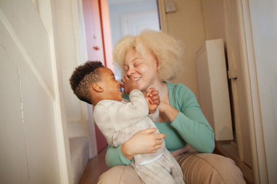Happy mother and son playing and laughing in hallway
