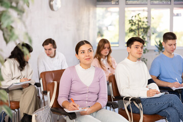 Portrait of attentive positive young female student attending training session in lecture class in college