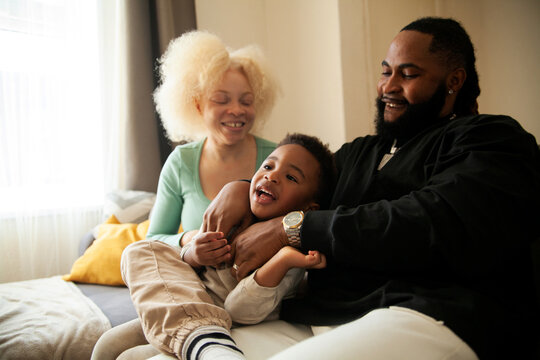 Happy African family hanging out in living room and laughing