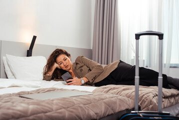 Beautiful business woman lying on bed in hotel room.
