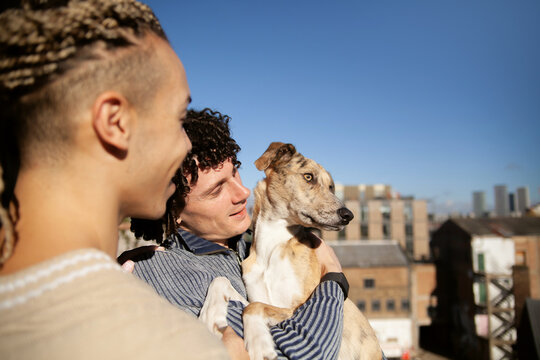 Family portrait of two men with their dog on rooftop