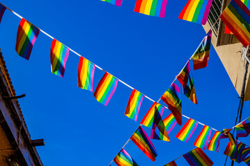 small rainbow flag against the sky in a Spanish city