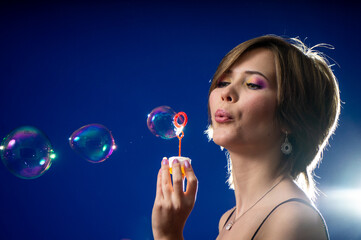 the girl throws soap bubbles. on a black background.