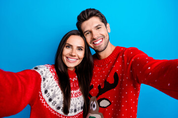 Photo portrait of lovely young spouses take selfie photo toothy smile wear x-mas ornament red sweaters isolated on blue color background
