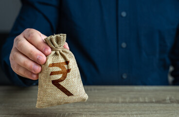 A man holds an indian rupee money bag. Deposits and savings. Loans and credits, mortgage. Economics...