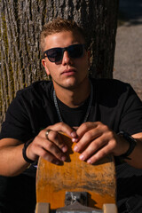 young skater looking at the camera while holding his skateboard © afloSolfa