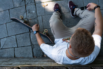 cool lifestyle concept. young man skater sitting on the street with his longboard