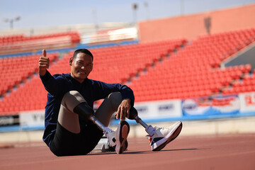 Asian male athlete with disability  rests on stadium track after run