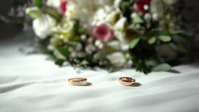 A pair of gold wedding rings in a glass casket box. Jewelry for a married couple. Vintage style. Bridal bouquet flowers