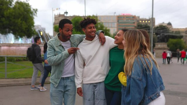 United group of college student friends having fun at city street. Multiracial people hugging each other laughing while hanging out outdoors. Youth community concept.