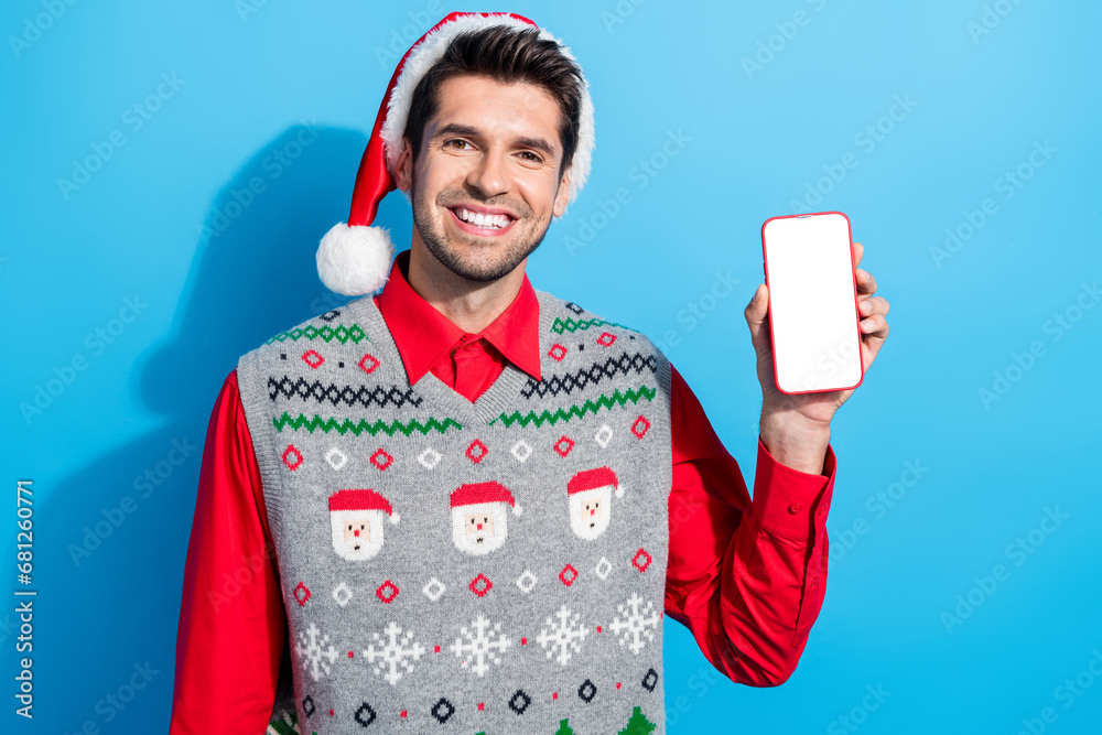 Poster photo of intelligent positive guy wear christmas hat demonstrate smartphone display qr code empty sp